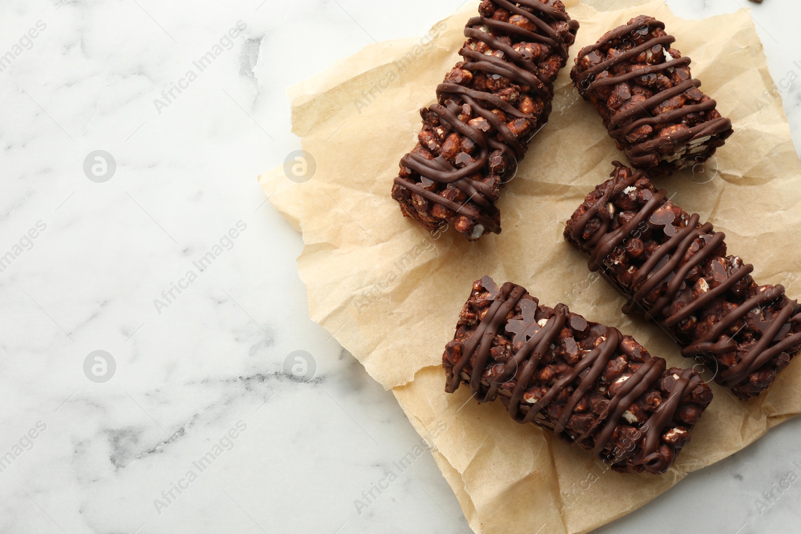 Photo of Delicious chocolate puffed rice bars on white marble table, top view. Space for text