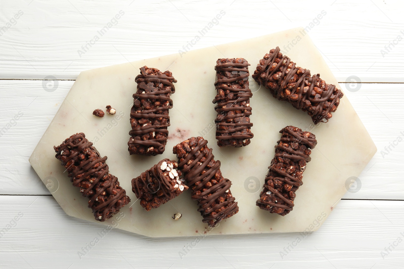 Photo of Delicious chocolate puffed rice bars on white wooden table, top view