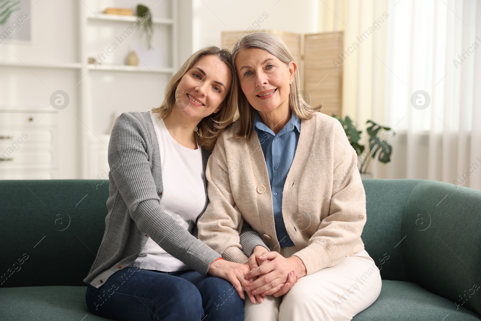 Photo of Family portrait of smiling mother and her daughter on sofa at home