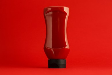 Photo of Ketchup in plastic bottle on red background