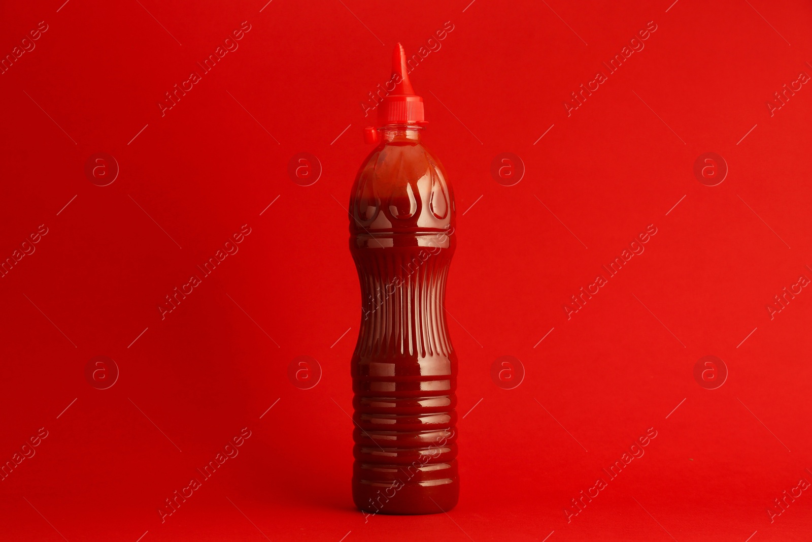 Photo of Ketchup in plastic bottle on red background