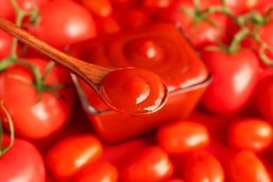 Photo of Spoon with delicious ketchup over tomatoes, closeup