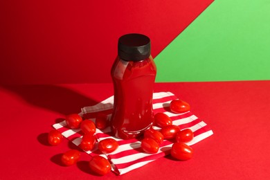 Photo of Bottle of ketchup and tomatoes on color background