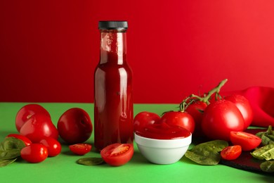 Photo of Ketchup, tomatoes and spinach on color background