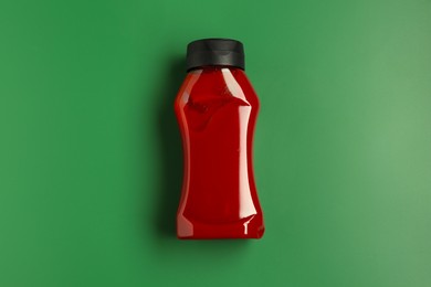 Photo of Bottle of ketchup on green background, top view