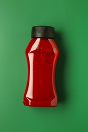 Photo of Bottle of ketchup on green background, top view