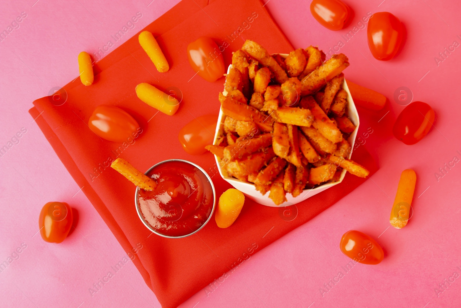 Photo of Tasty ketchup, tomatoes and fried carrots on pink background, flat lay