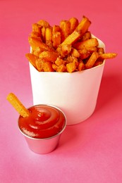 Photo of Tasty ketchup and fried carrots on pink background