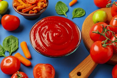 Photo of Tasty ketchup and vegetables on blue background, closeup