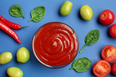 Photo of Tasty ketchup and vegetables on blue background, flat lay