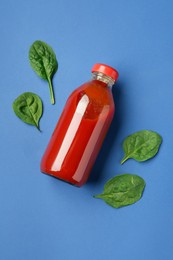 Photo of Tasty ketchup in bottle and basil on blue background, flat lay