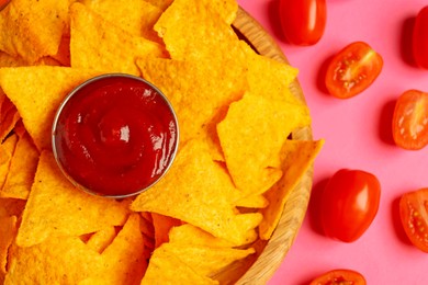 Photo of Tasty ketchup, tomatoes and nachos on pink background, flat lay