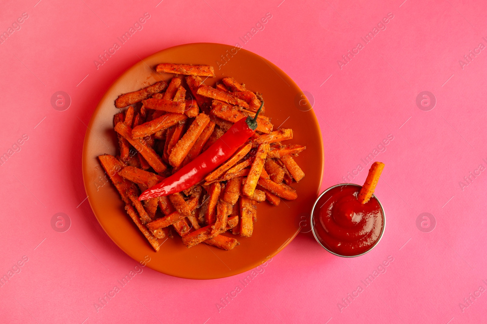 Photo of Tasty ketchup and fried carrots on color background, top view