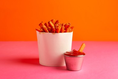 Photo of Tasty ketchup and fried carrots on color background