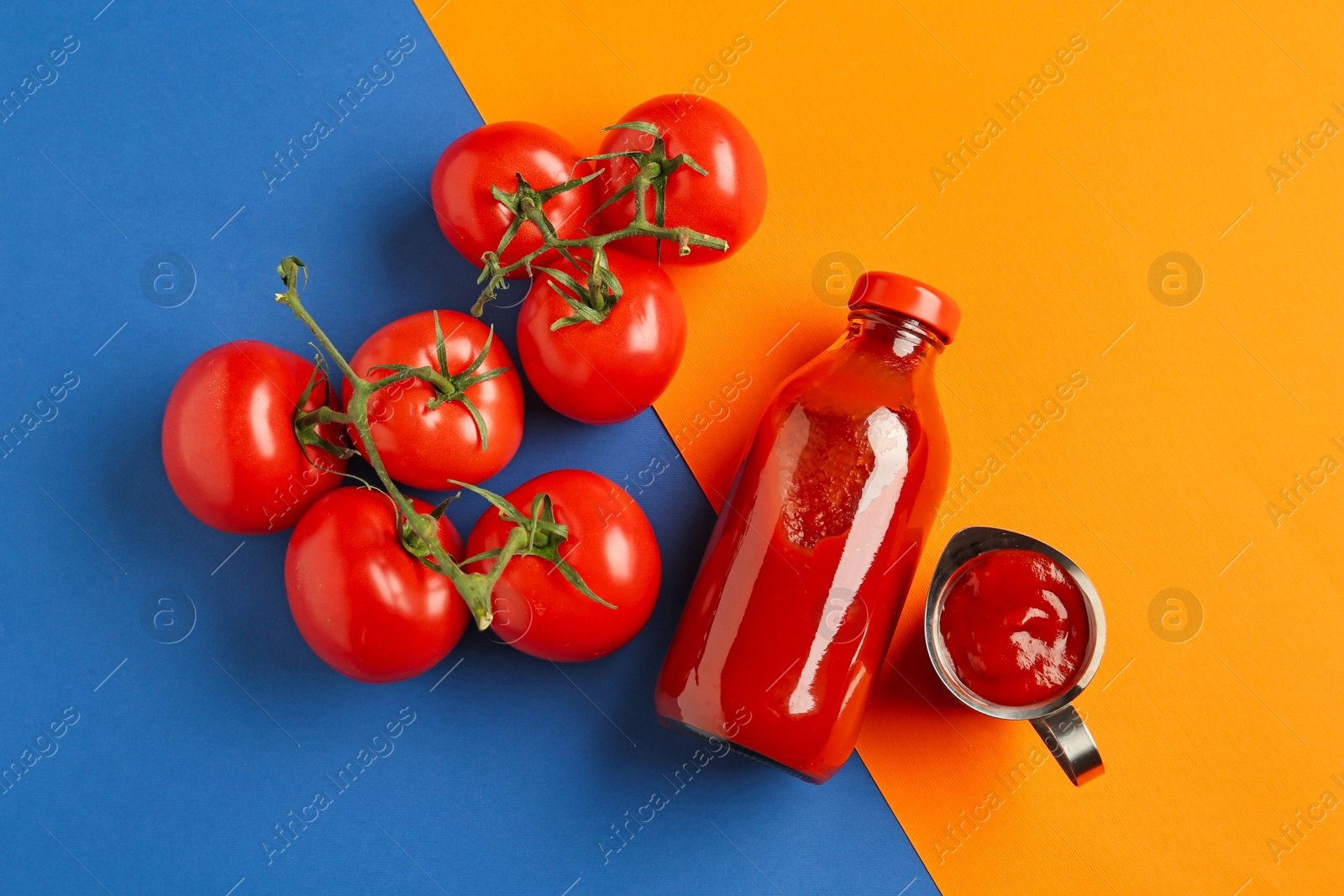 Photo of Tasty ketchup and tomatoes on color background, flat lay