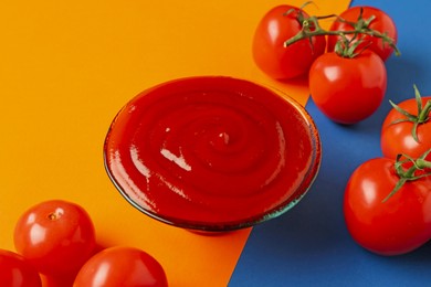 Photo of Tasty ketchup and tomatoes on color background, closeup