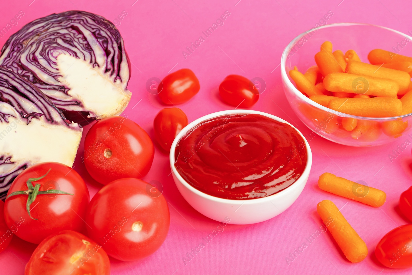 Photo of Tasty ketchup and vegetables on pink background, closeup