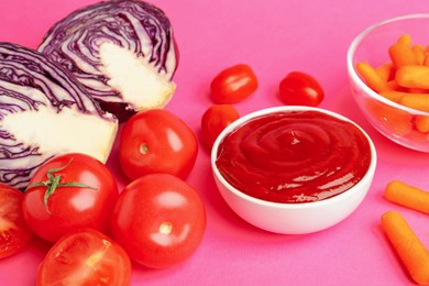 Photo of Tasty ketchup and vegetables on pink background, closeup