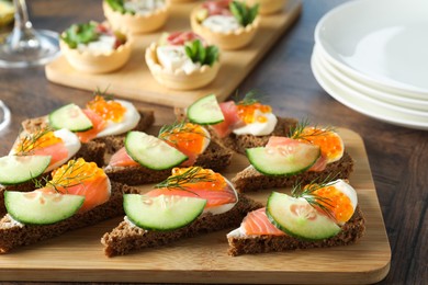 Photo of Tasty canapes with salmon and cucumber on wooden table, closeup