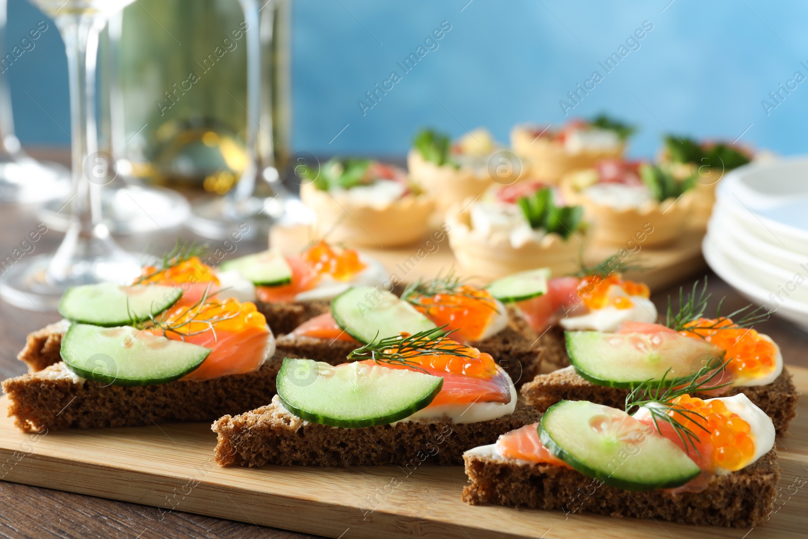 Photo of Tasty canapes with salmon and cucumber on wooden table, closeup