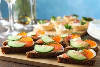 Photo of Tasty canapes with salmon and cucumber on wooden table, closeup