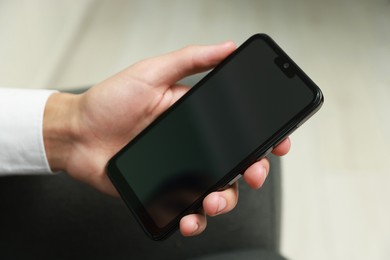 Photo of Man using smartphone with blank screen indoors, closeup