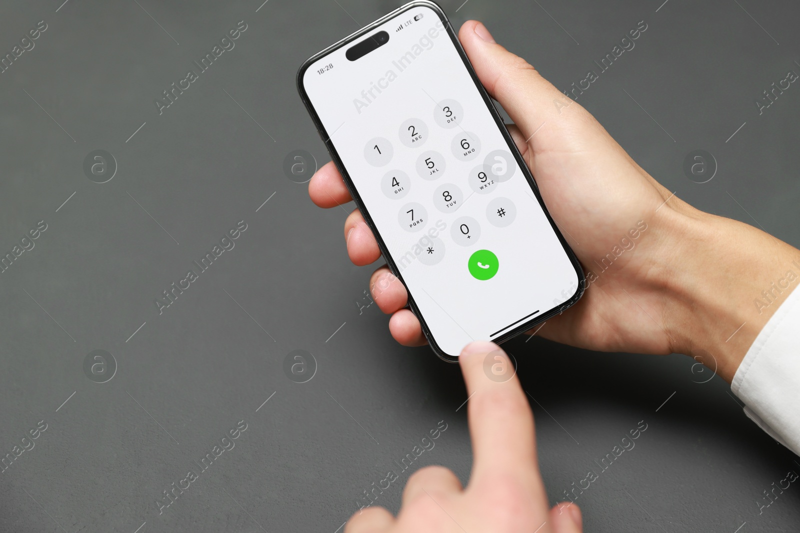 Photo of Man dialing number on smartphone at grey table, closeup. Space for text