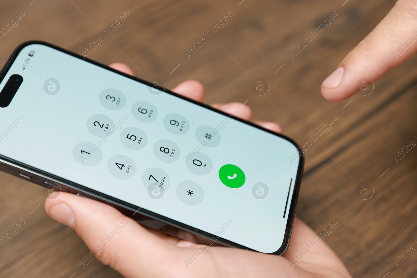 Photo of Man dialing number on smartphone at wooden table, closeup