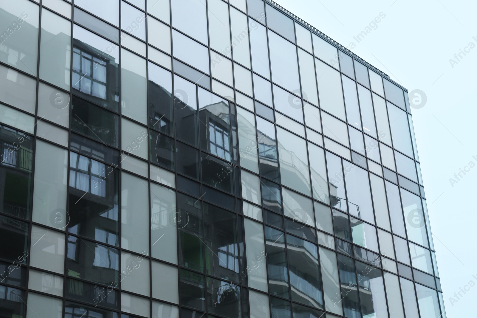 Photo of Modern building with many windows against blue sky, low angle view