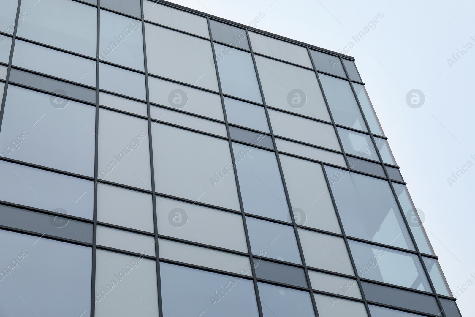 Photo of Modern building with many windows against blue sky, low angle view