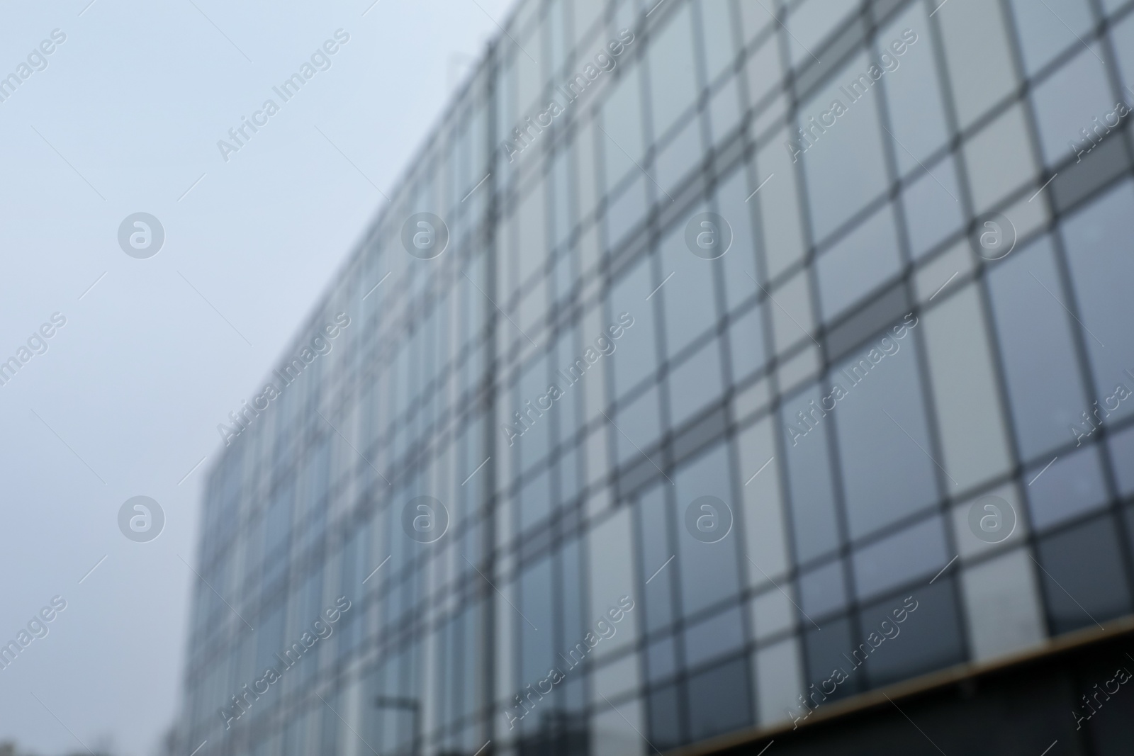 Photo of Blurred view of modern building with many windows against blue sky