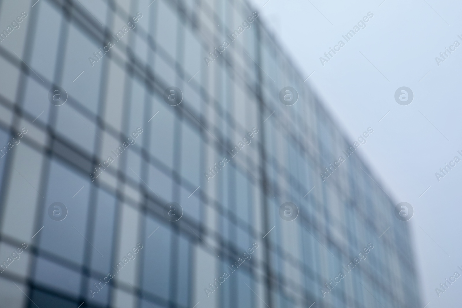 Photo of Blurred view of modern building with many windows against blue sky