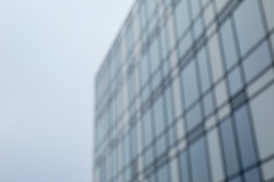 Photo of Blurred view of modern building with many windows against blue sky, space for text