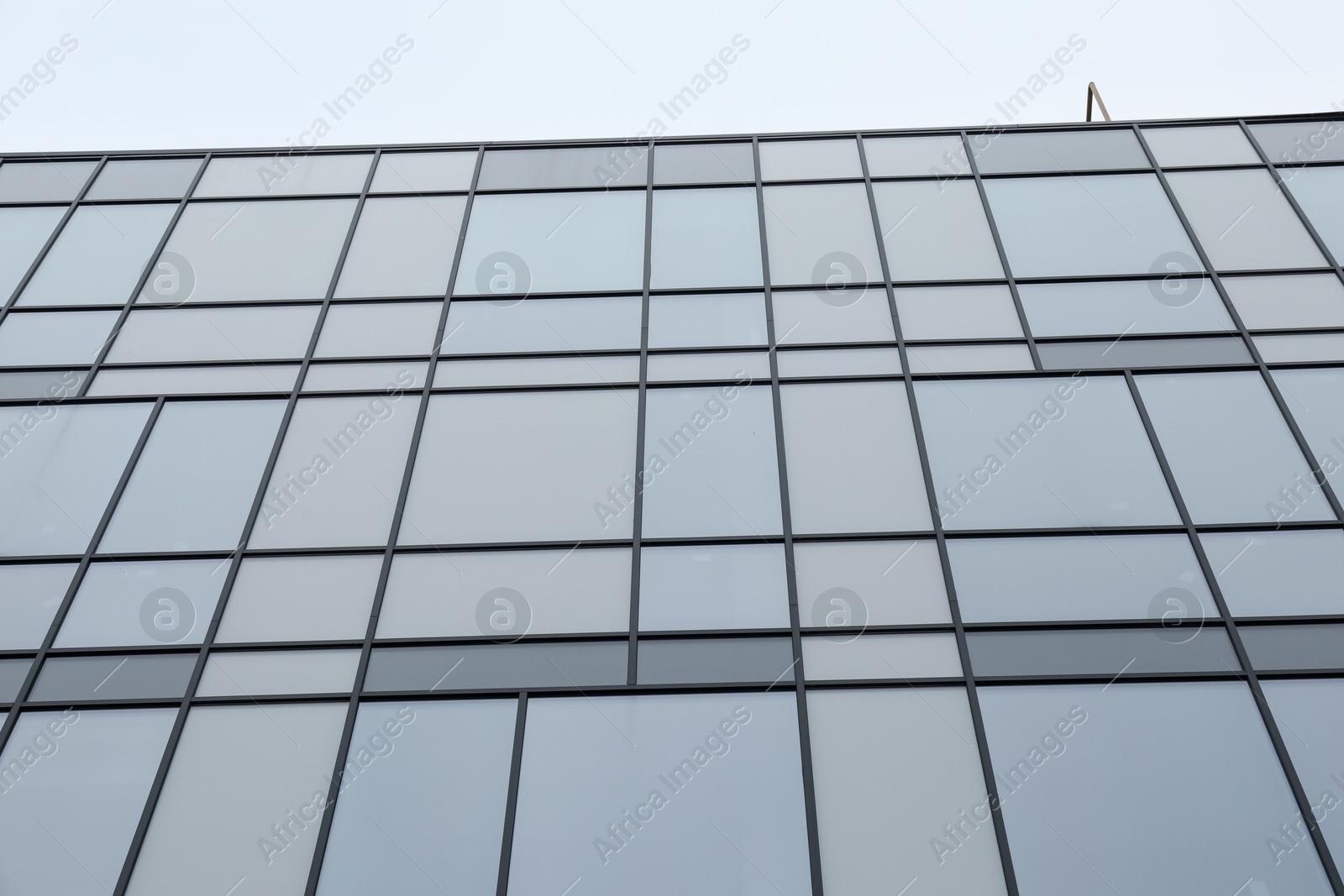 Photo of Modern building with many windows against blue sky, low angle view