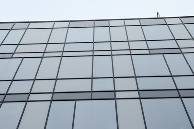 Photo of Modern building with many windows against blue sky, low angle view