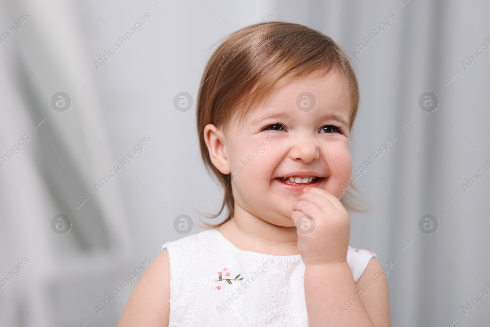 Photo of Cute little baby girl on light grey background