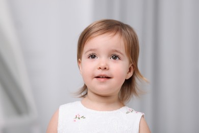 Photo of Cute little baby girl on light grey background