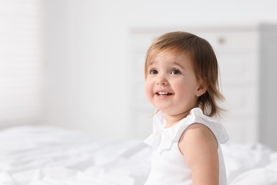 Photo of Cute little baby girl on bed at home. Space for text