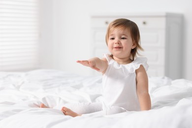 Photo of Cute little baby girl on bed at home. Space for text