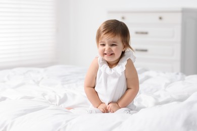 Photo of Cute little baby girl on bed at home. Space for text