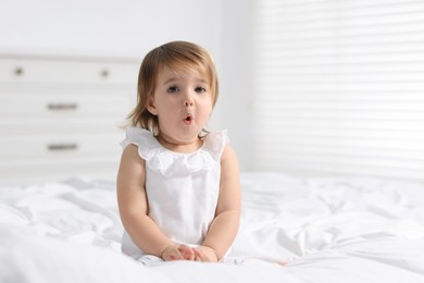 Photo of Cute little baby girl on bed at home. Space for text