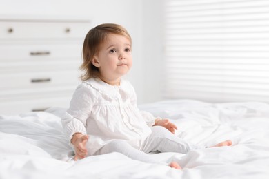 Photo of Cute little baby girl on bed at home. Space for text