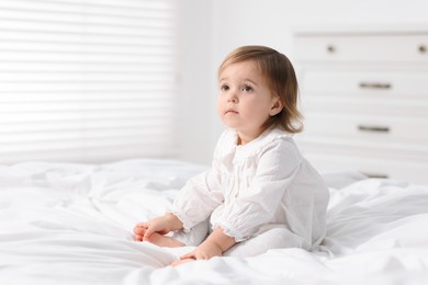 Photo of Cute little baby girl on bed at home. Space for text