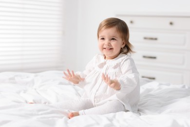 Photo of Cute little baby girl on bed at home. Space for text