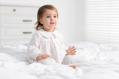 Photo of Cute little baby girl on bed at home. Space for text