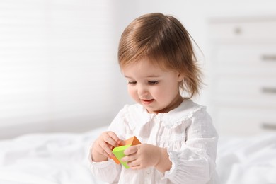 Photo of Cute little baby girl playing with toy on bed at home