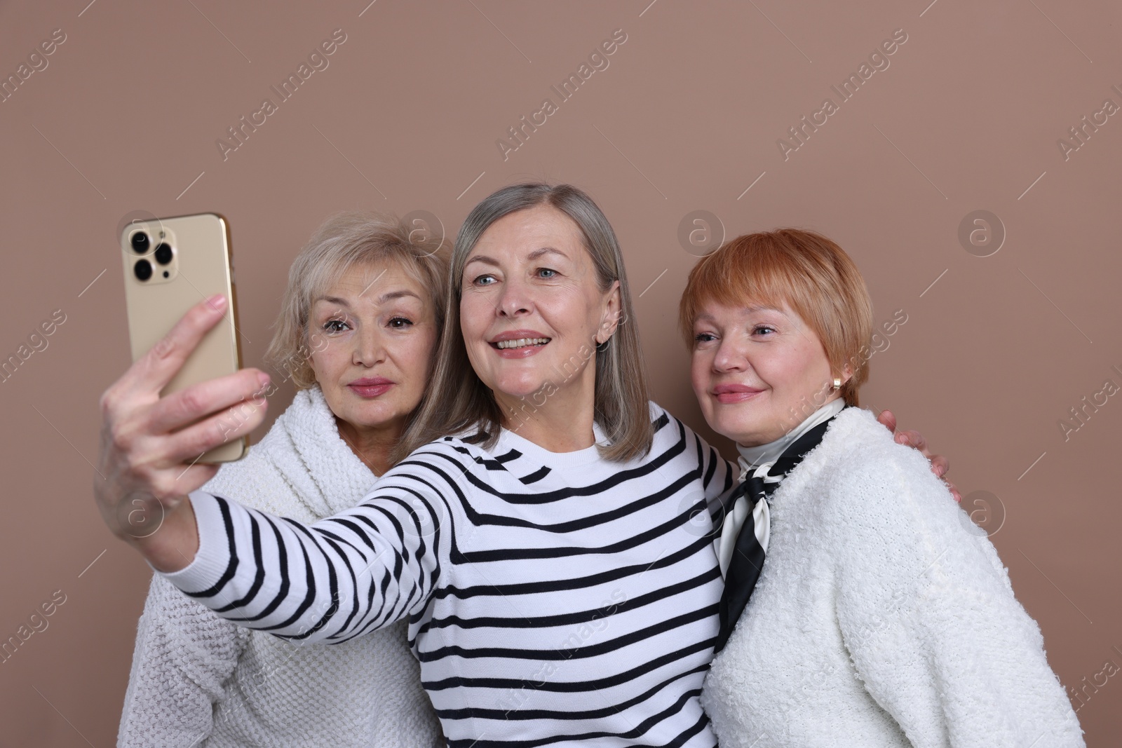 Photo of Friendship. Senior women taking selfie on dark beige background