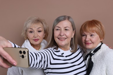 Photo of Friendship. Senior women taking selfie on dark beige background