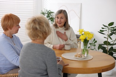 Photo of Friendship. Senior women enjoying hot drinks at table indoors