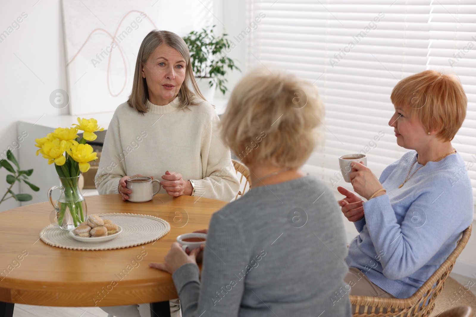 Photo of Friendship. Senior women enjoying hot drinks at table indoors